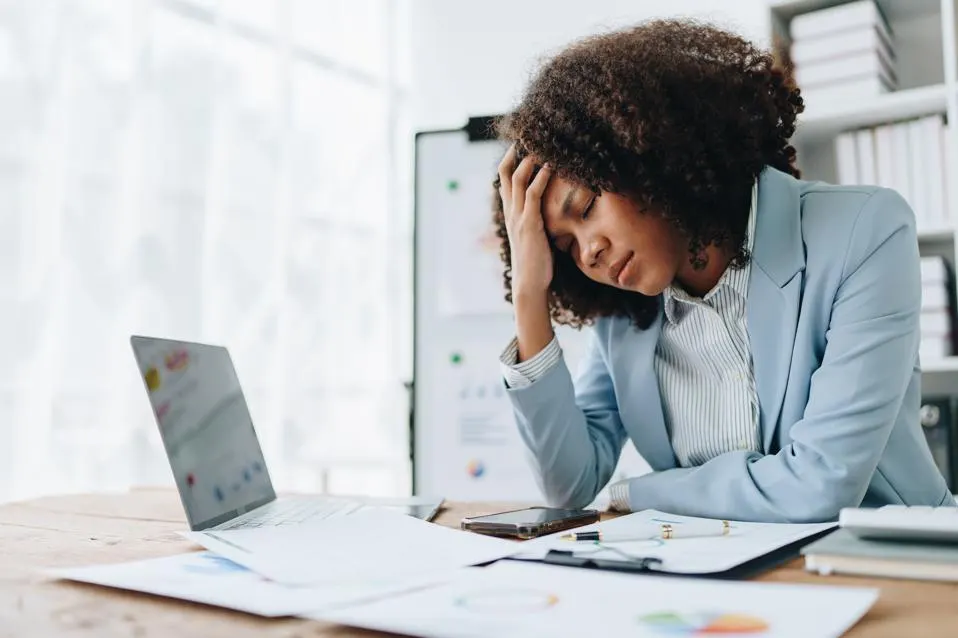 Stressed businesswoman overwhelmed with paperwork during economic uncertainty.