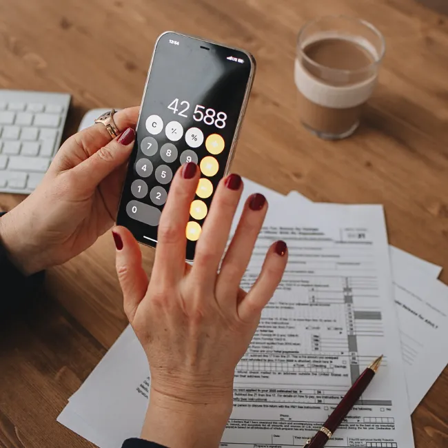 A person reviewing their financial binder at a desk with coffee